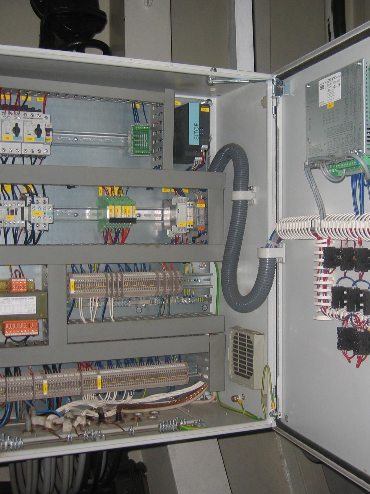 Kapağı açık PLC otomasyon panosu; klemens sırası, PLC ve besleme montajı