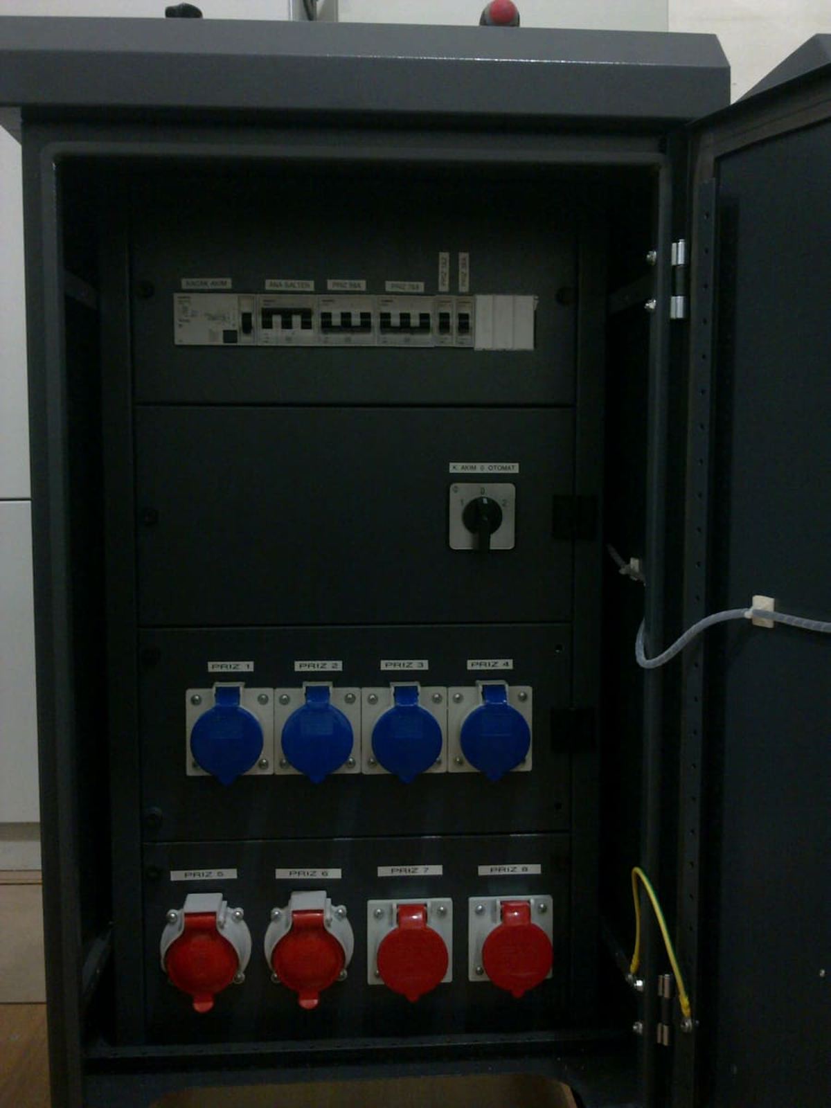 Kapağı açık şantiye panosu; içeride otomatik sigortalar, kaçak akım rölesi ve priz bağlantıları